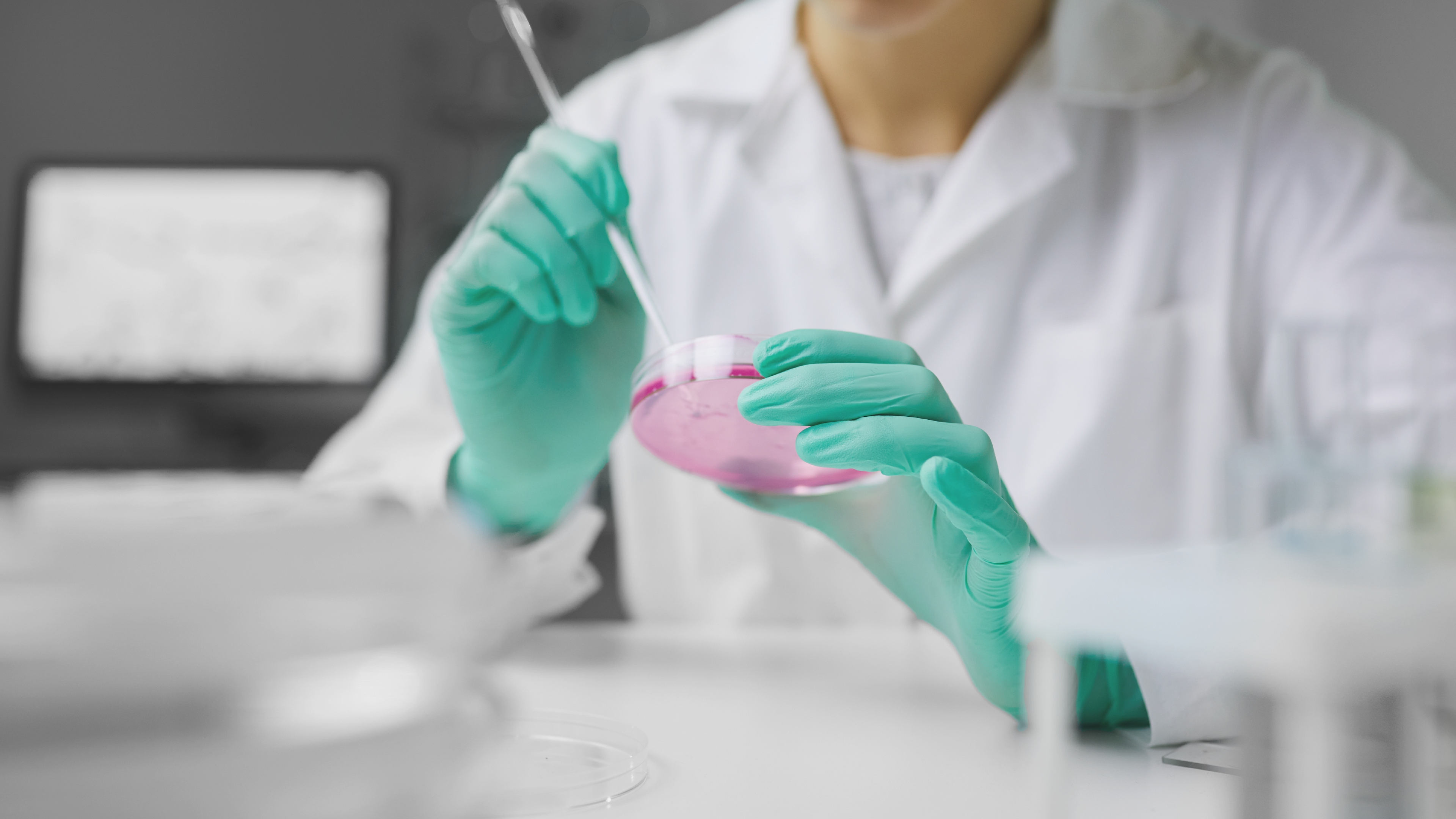 Imagen de mujer en bata blanca realizando pruebas en una placa de Petri